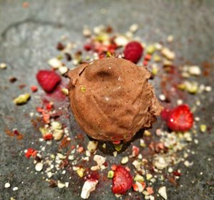 Delicious Nice-cream. A ball of Chocolate and Banana Nice-cream with a nut and raspberry garnish